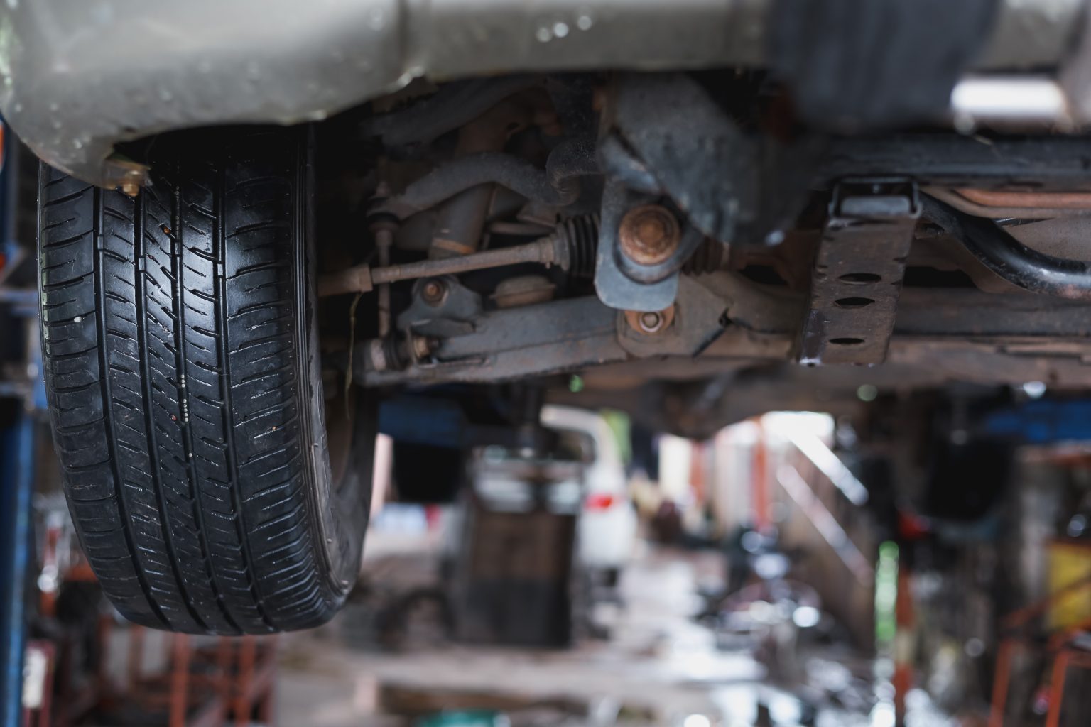 The undercarriage of a car with a jack is lifted for mot.